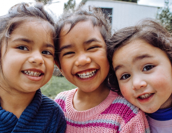Three children smile at the camera