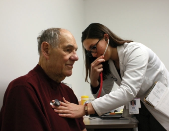 A Pitt medical student uses a stethoscope to listen to a patient's chest